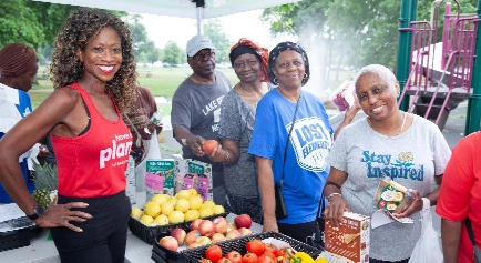 Elizabeth Madison standing with women while handing out fresh fruit and vegetables