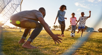 Family playing soccer at the park